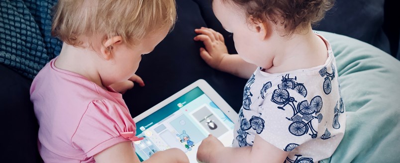 Two babies playing with a computer tablet