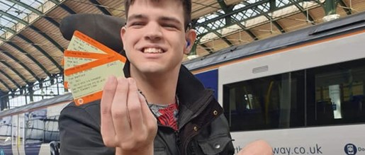 A man holding some train tickets whilst smiling