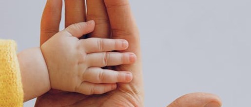 A baby's hand being held in a larger hand